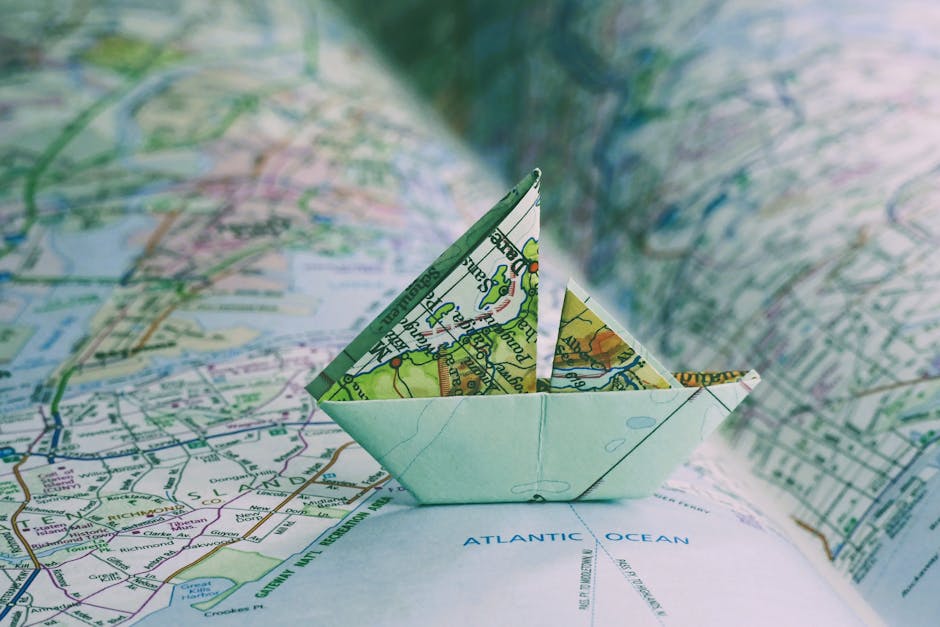 Close-up of an origami boat placed on an open map, highlighting travel and exploration.